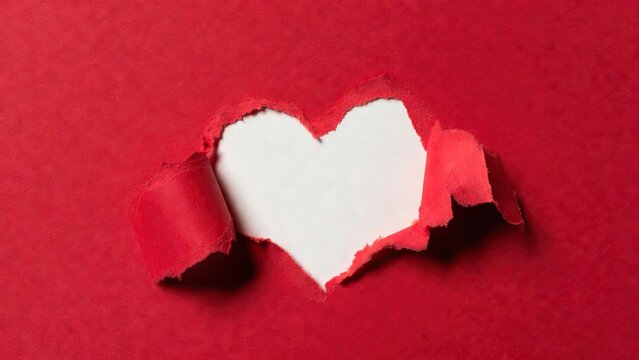 A striking red paper background features a dramatic heart-shaped rip in its center, revealing a pristine white layer beneath.