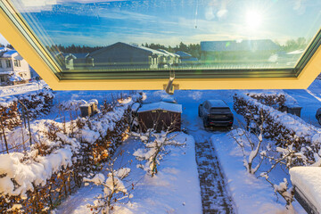 Beautiful view of snowy garden and parked car through open villa window with bright winter sunlight and blue sky. Sweden.