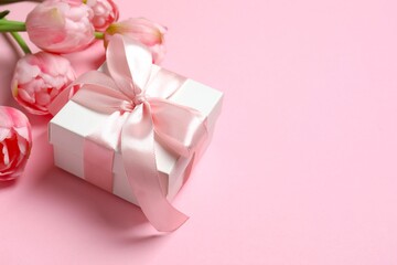 Beautiful fresh tulips with gift box card on pink background