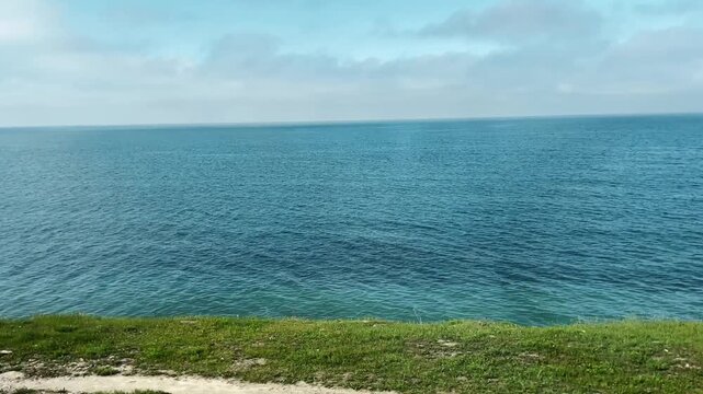 View of the Black Sea coastline in spring seen from a moving train along the Tuapse to Sochi railway. Concept of travel, slow journey, coastal nature, and peaceful seaside landscape