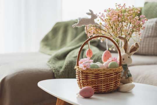 Easter Basket with Ester Eggs,  Plush Bunny and Spring Decor on White Table intoCozy Living Room