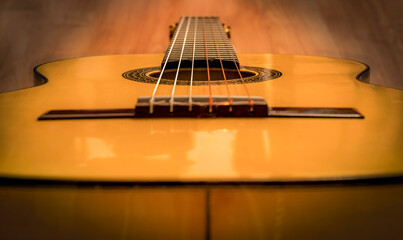 Classical Spanish guitar on wooden floor with blurred background