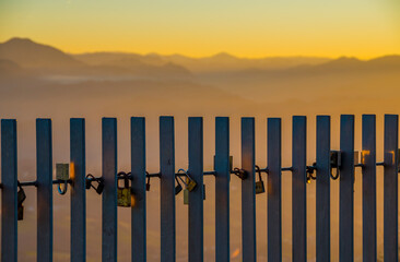 Love locks on fence at sunset with blurred mountains in background