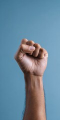Obraz premium Raised caucasian male fist against blue background symbolizing solidarity and strength