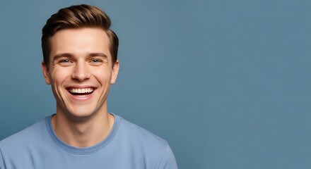 Smiling young man with brown hair and blue shirt against a blue background.