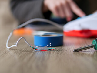Shallow Focus Detail of Electrical Wires and Tools on a Wooden Table - Close-Up of a Child Working with Wires and Blue Tape