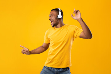 African American Male Having Fun Dancing Enjoying Music Posing Wearing Wireless Earphones Over Yellow Background In Studio. Great Musical Application, Favorite Playlist