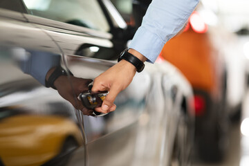 Unrecognizable man open car door, closeup of male hand with watch unlocking black auto door, making...