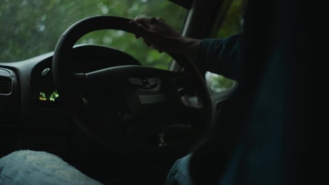 closeup hand on steering wheel cinematic rainy drive inside car interior, denim sleeve, wet windshield, glowing dashboard lights, moody introspective atmosphere, slow panning broll footage capturing