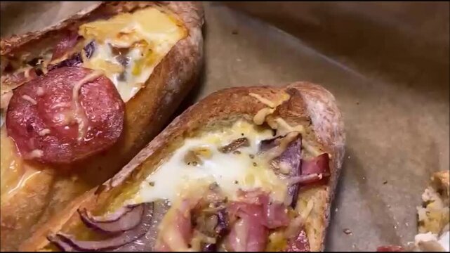 Detailaufnahme von halbierten Brot, gef&uuml;llt mit ei,  K&auml;se, Speck und Salami. Die goldbraun &uuml;berbackene Oberfl&auml;che und die rustikale Pr&auml;sentation vermitteln Hausmannskost, Genuss und herzhaftes Co