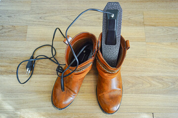 Electric shoe dryer insoles inserted inside ankle boots for efficient drying process. Illustrates heated drying technology, interior moisture extraction,  bacteria elimination, and hygiene practices.