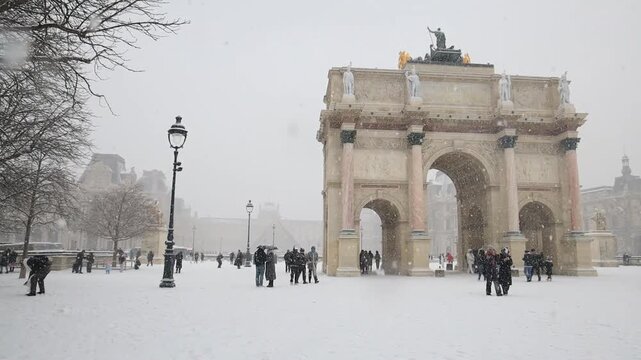 People in snow near Arc de Triomphe du Carrousel in Paris, France in wintertime