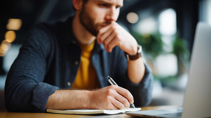 Closeup portrait faceless handsome man working from home office taking reading writing notes notepad with laptop computer casual businessman entrepreneur focused