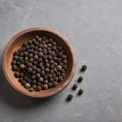 A rustic wooden bowl filled with whole black peppercorns rests 