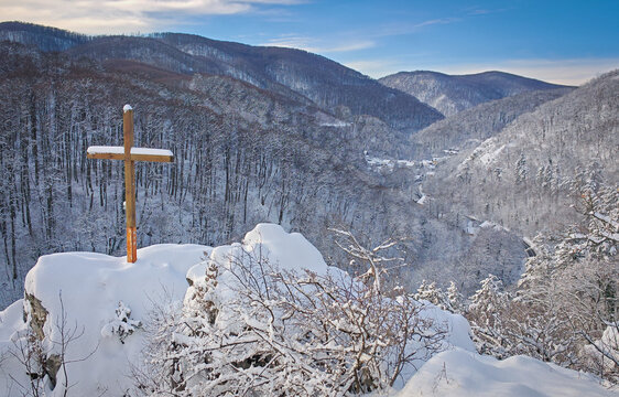 Wooden cross on the snow-covered Moln&aacute;r Rock overlooking the winter forest and the village of Als&oacute;h&aacute;mor in the B&uuml;kk Mountains, Hungary.