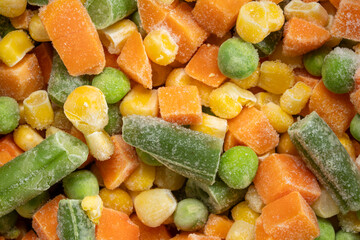closeup background and texture of frozen vegetable medley - carrots, peas, green beans and corn