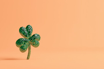 Green sequined four-leaf clover stands upright against a soft peach background, symbolizing luck and prosperity, ideal for festive celebrations and seasonal decor