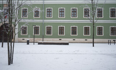 Cluj-Napoca/Romania. 1/07/2026: Snow covered pedestrian area next to historic green building in winter