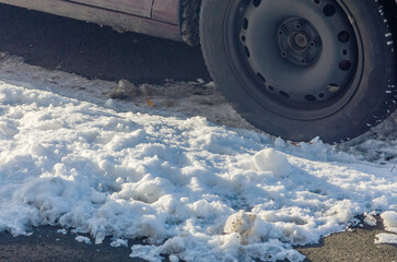 Car wheel on roadside in dirty snow highlighting winter road grime and muddy conditions