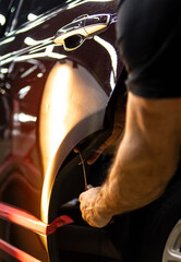 Process of paintless dent repair on car body. The mechanic at the auto shop with tools to repair dents in car body. Body repair. A specialist repairs a dent on the car body without painting. PDR. 