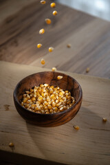Falling corn seeds into a bowl, preparation of popcorn at home. Making flour from organic ingredients