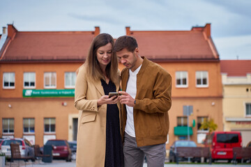 Man and woman checking smartphone while standing in city center