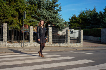 Woman crossing street on pedestrian crosswalk in sunlight