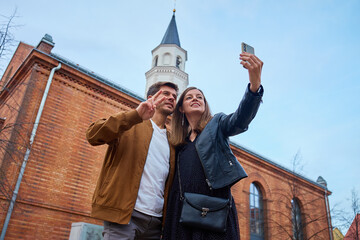 Couple taking selfie with smartphone near brick building