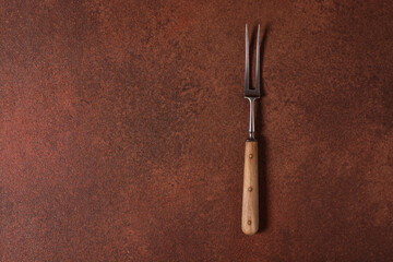 vintage meat fork on brown background