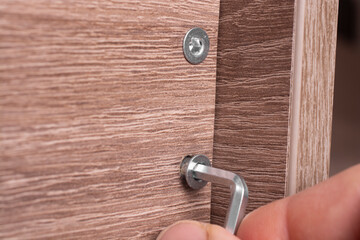 A furniture maker tightens furniture with confirmats using a hex key