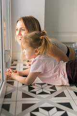 Mother and daughter sitting near the window and talking quietly. Emotional connection, warmth, and the peaceful rhythm of daily family life at home.