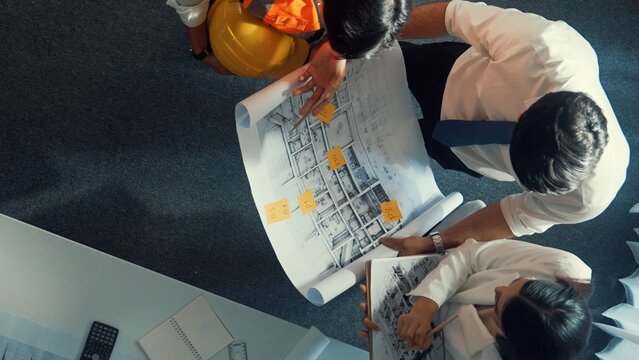 Top down view of smart architect engineer team looking at building design at meeting. Group of diverse designer team working together and discussing about house interior while standing. Alimentation. - Powered by Adobe