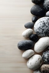 Overhead View of Smooth Dark Gray and Light Gray Pebbles Artistically Arranged on a Pale Wood Background for Tranquil Decor and Balance
