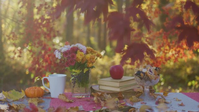 Autumn mood on outdoor table. Cozy fall ambiance with books. Warm autumn table arrangement. Fall treats on cozy table. Autumn table with bouquet.