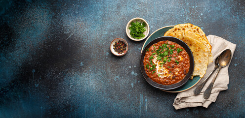 Traditional Indian Punjabi dish Dal makhani with lentils and beans in black bowl served with naan