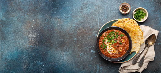 Traditional Indian Punjabi dish Dal makhani with lentils and beans in black bowl served with naan