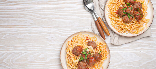 Two plates of delicious spaghetti with meatballs served on white wooden table top view copy space