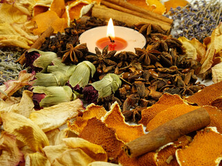 Dried herbs, flowers, spice, orange peel and scented candle, side view, background. Ingredients for air freshening and relaxation.
 