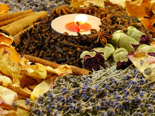 Dried herbs, flowers, spice, orange peel and scented candle, side view, background. Ingredients for air freshening and relaxation.
 