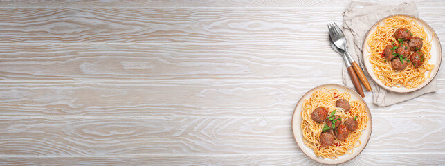 Two plates of delicious spaghetti with meatballs served on white wooden table top view copy space