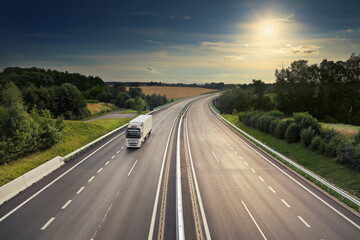 Large Transportation Truck on a highway road through the countryside at sunset

