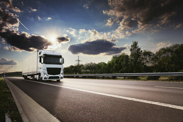 Large Transportation Truck on a highway road through the countryside at sunset
