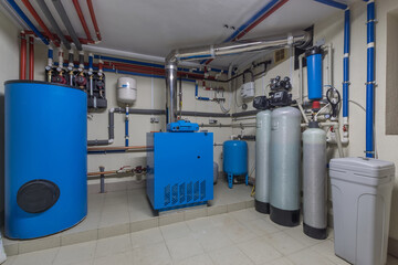 A water pump system is set up in a basement with blue tanks and silver pipes. Various valves and...