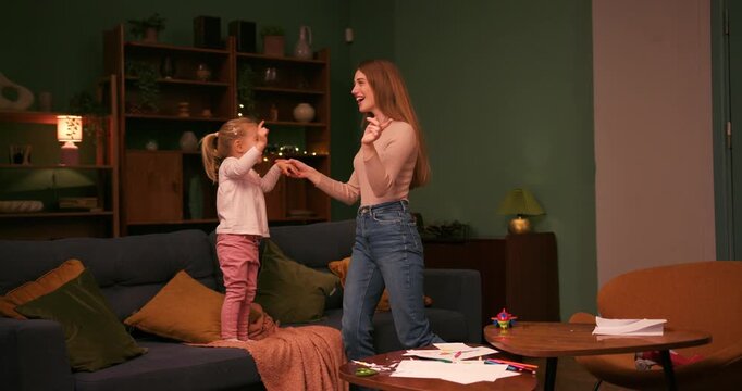 Young mother and daughter jumping on the couch at home