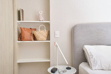 Modern bedroom interior showing organized shelving unit, bedside table with lamp, and bed