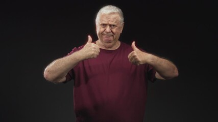 Man gives double thumbs up with visible thumbs and forearms in studio wearing burgundy tshirt amid varied facial expressions; hesitation humor.