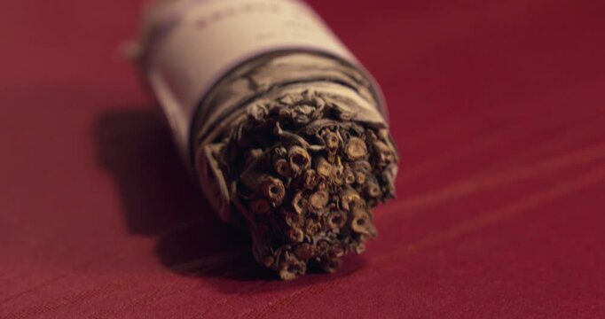 Dried herbal bundle on red surface close up