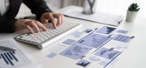 A business professional engages with digital data charts and graphs in a modern office workspace,...