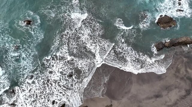 Above View of Volcanic Beach with Rocks and Atlantic Ocean in North Tenerife. Pull-back Shot of Sea Waves and Black Sand Shore in Canary Islands.