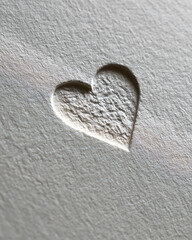 Heart shape embossed on textured white paper